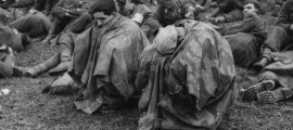 28th March 1945:  Tired and disconsolate German prisoners of war crouch under waterproof capes after their capture on the banks of the Rhine.  (Photo by Fred Ramage/Keystone/Getty Images)