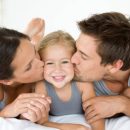 Father and mother kissing daughter