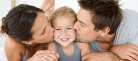 Father and mother kissing daughter